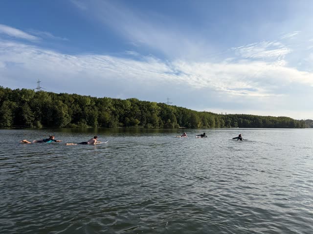 Sechs Paddler in einer Reihe auf dem weiten See
